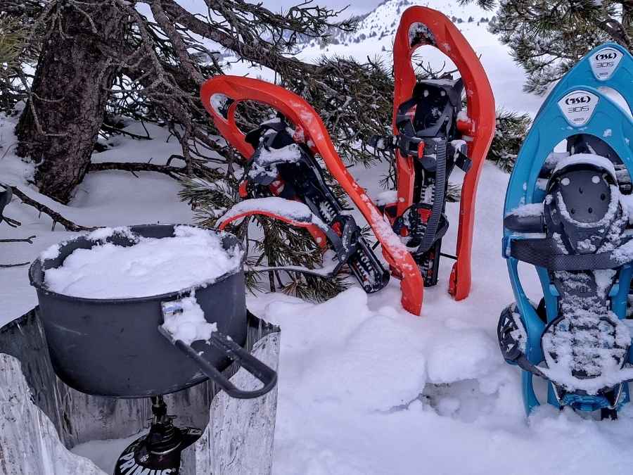 neige qui fond pour faire de l'eau sur un réchaud, des raquettes à neige à côté