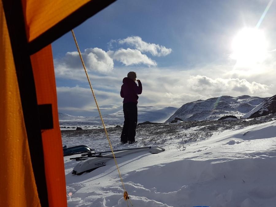 vue depuis l'intérieur de la tente en hiver, personne qui se lave les dents devant le paysage ensoleillé